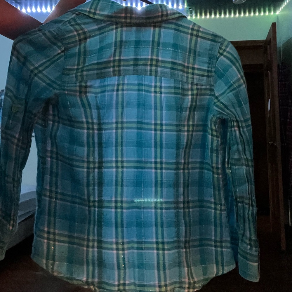A button up sweater. It is green and blue with thin silver glitter lines